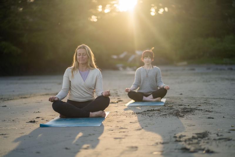 two women meditating on a beach in tofino
